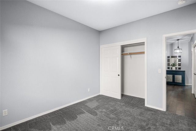 unfurnished bedroom with a closet, baseboards, lofted ceiling, and dark carpet