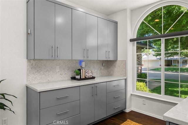 kitchen with dark wood finished floors, gray cabinetry, a wealth of natural light, and tasteful backsplash