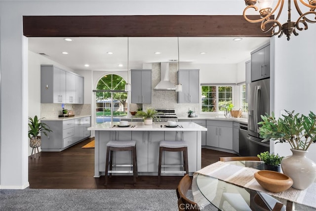 kitchen featuring wall chimney range hood, stainless steel fridge with ice dispenser, a center island, and gray cabinets