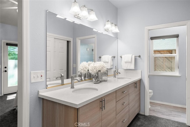 bathroom with double vanity, toilet, and a sink