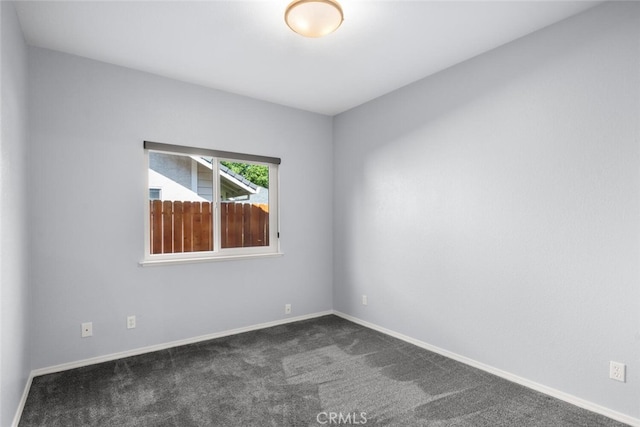 empty room with baseboards and dark carpet