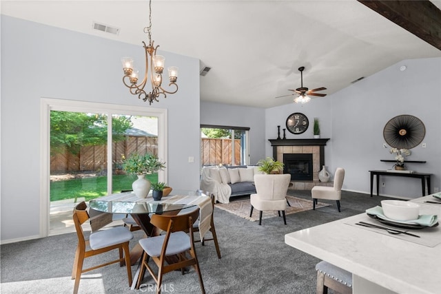 dining room with lofted ceiling, ceiling fan with notable chandelier, visible vents, carpet flooring, and a tile fireplace