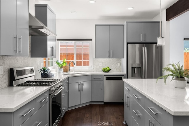kitchen featuring a sink, stainless steel appliances, gray cabinetry, and wall chimney exhaust hood
