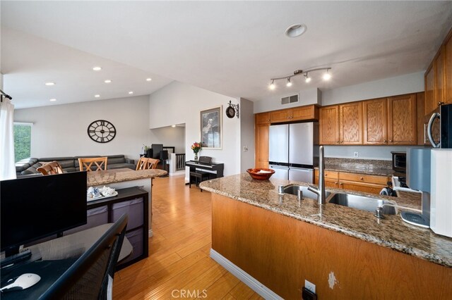 15796 Midwood Dr Unit 6, Granada Hills, CA 91344 - kitchen with appliances with stainless steel finishes, brown cabinetry, a sink, open floor plan, and vaulted ceiling