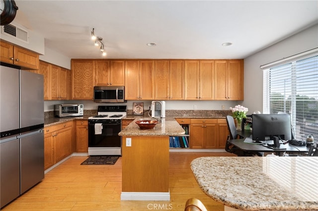 15796 Midwood Dr Unit 6, Granada Hills, CA 91344 - kitchen with appliances with stainless steel finishes, a peninsula, light wood-style flooring, light stone counters, and brown cabinets