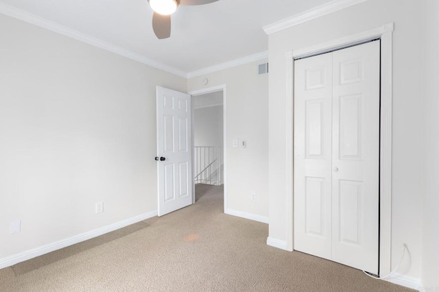 unfurnished bedroom featuring a closet, baseboards, ornamental molding, visible vents, and light colored carpet