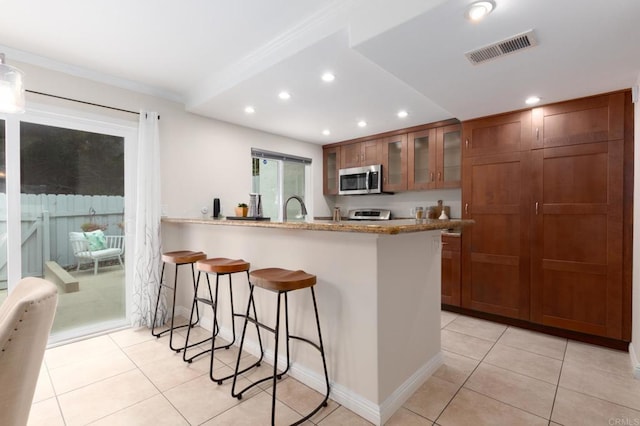 827 Del Mar Downs Rd Unit E, Solana Beach, CA 92075 - kitchen featuring stainless steel microwave, a breakfast bar area, recessed lighting, light tile patterned floors, and a sink