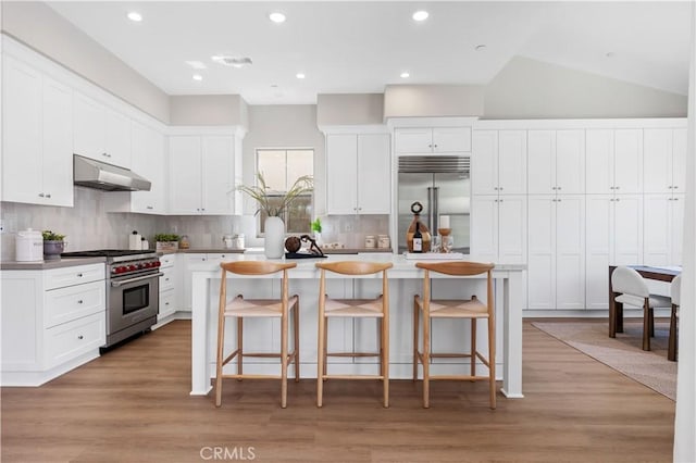149 Fairgreen, Irvine, CA 92618 - kitchen with high end appliances, under cabinet range hood, a center island, decorative backsplash, and a breakfast bar area