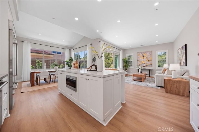 149 Fairgreen, Irvine, CA 92618 - kitchen featuring stainless steel oven, healthy amount of natural light, light wood-style floors, white cabinetry, and vaulted ceiling