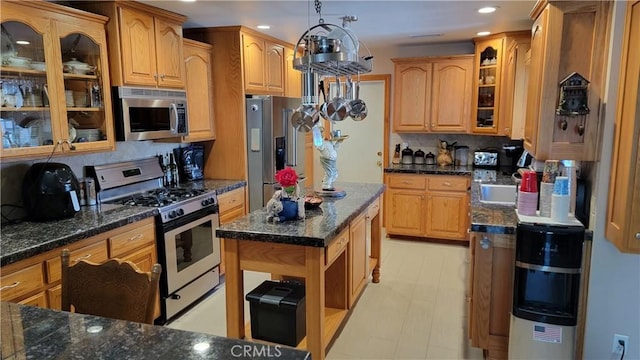 kitchen with appliances with stainless steel finishes, dark stone counters, glass insert cabinets, and recessed lighting