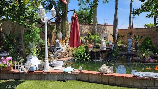 view of community with a fenced backyard and a garden pond