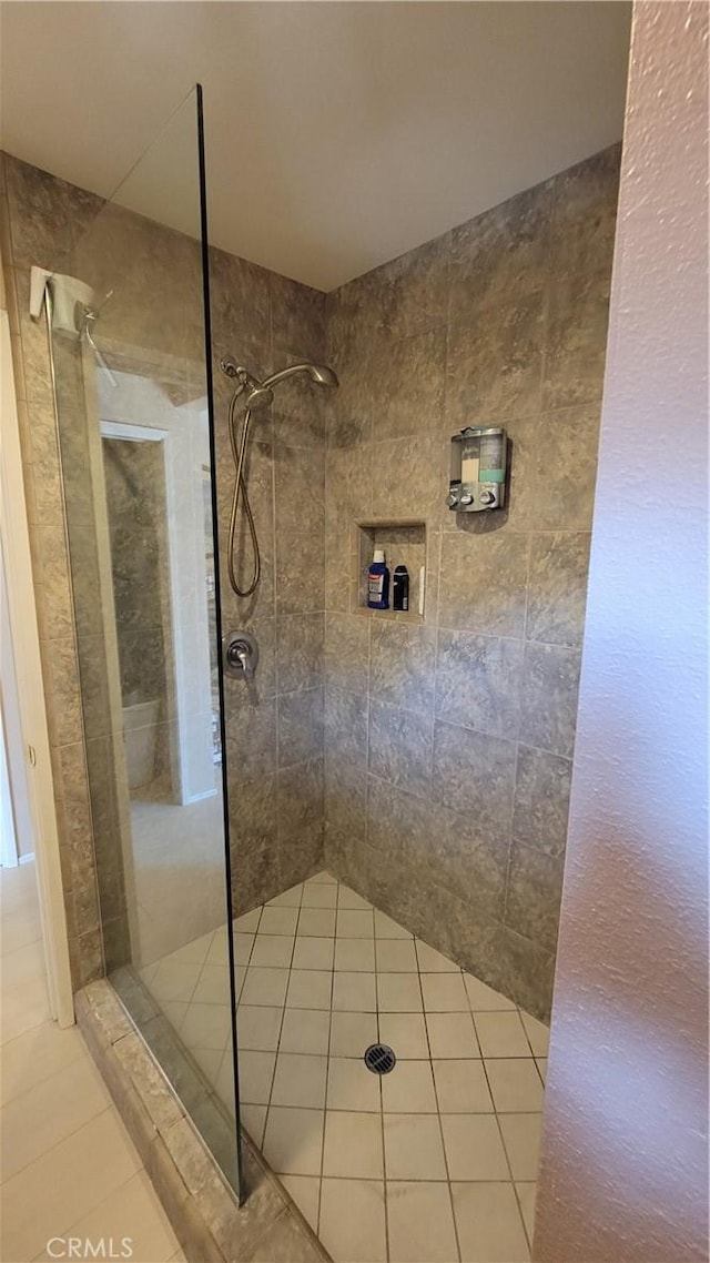 bathroom with a tile shower and tile patterned flooring