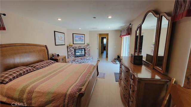 bedroom with recessed lighting, light wood-style floors, and a fireplace