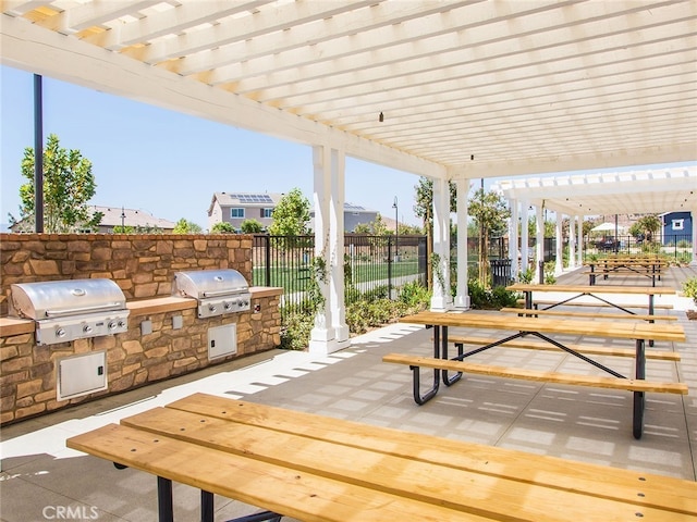 view of patio featuring grilling area, an outdoor kitchen, fence, and a pergola