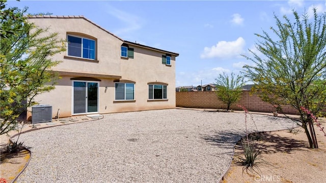 rear view of house with central AC unit, stucco siding, and a fenced backyard