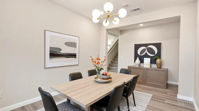 dining room featuring a chandelier, stairway, light wood finished floors, and baseboards