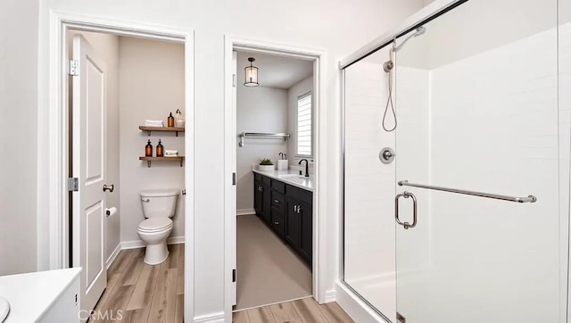 full bath featuring a shower stall, wood finished floors, toilet, and vanity