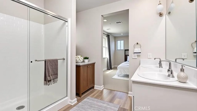 bathroom with a stall shower, connected bathroom, wood finished floors, and vanity