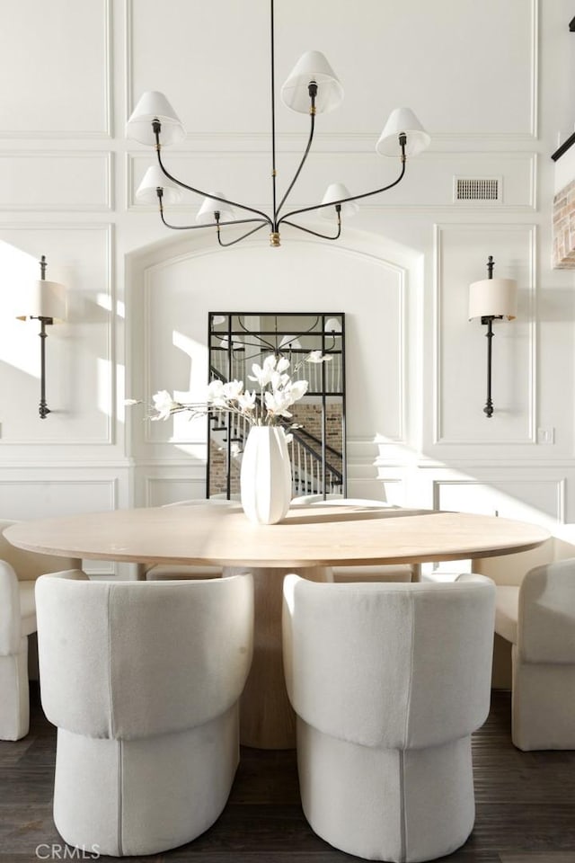 dining room featuring a decorative wall, a notable chandelier, dark wood-style floors, and visible vents