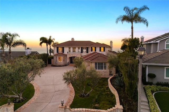 mediterranean / spanish-style home with driveway and a chimney