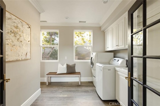 laundry room featuring cabinet space, washing machine and clothes dryer, crown molding, visible vents, and baseboards