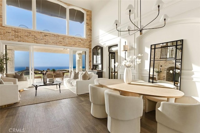dining space with wood finished floors, a towering ceiling, and a notable chandelier