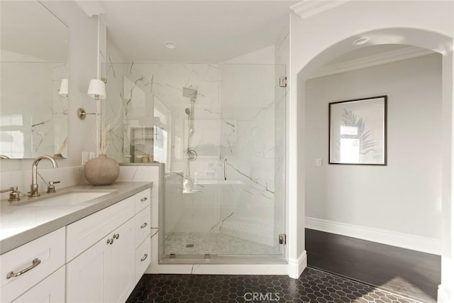 full bathroom featuring a marble finish shower, ornamental molding, vanity, and baseboards
