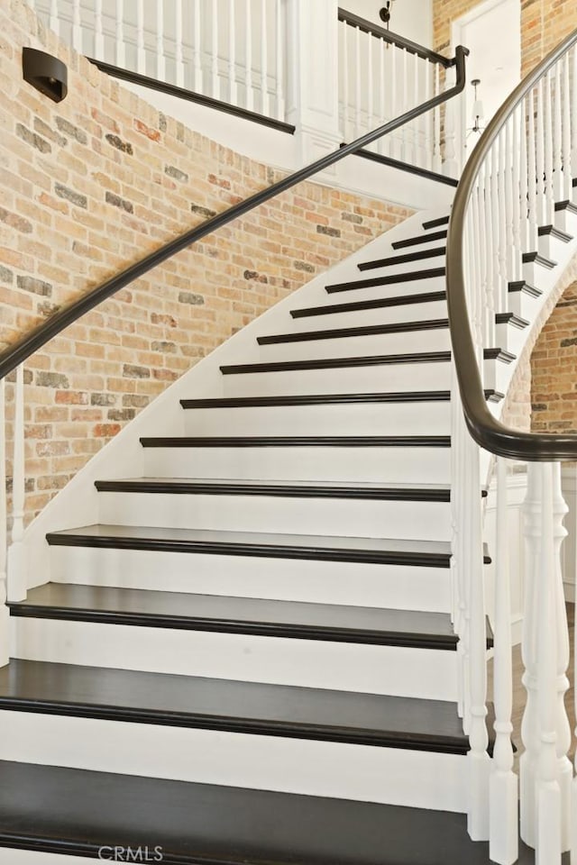 stairs featuring brick wall and a towering ceiling