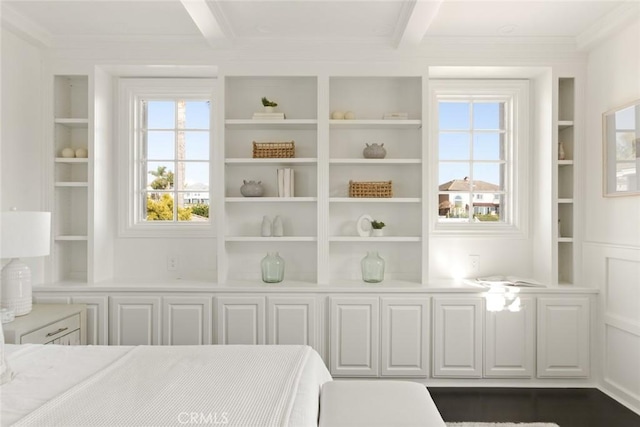 unfurnished bedroom with multiple windows, beam ceiling, and ornamental molding