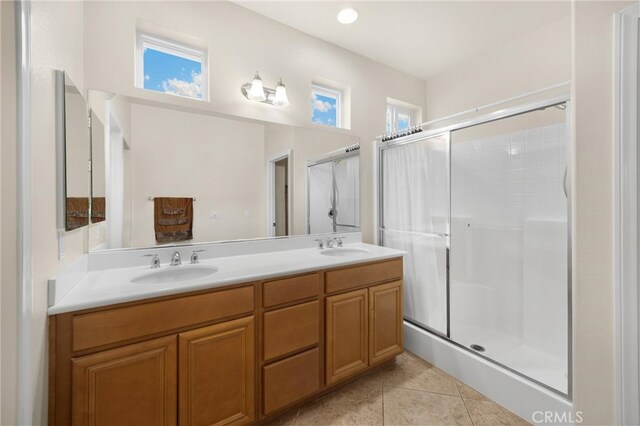 full bath featuring a sink, tile patterned flooring, double vanity, and a shower stall