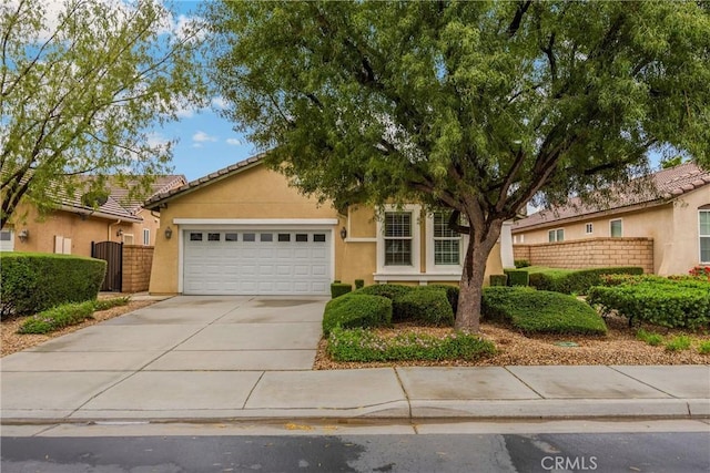 view of front of property featuring concrete driveway, a garage, stucco siding, and fence