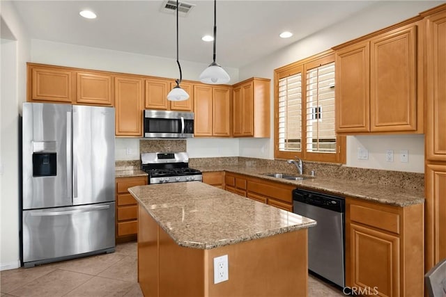 kitchen featuring a sink, light stone counters, visible vents, a kitchen island, and appliances with stainless steel finishes