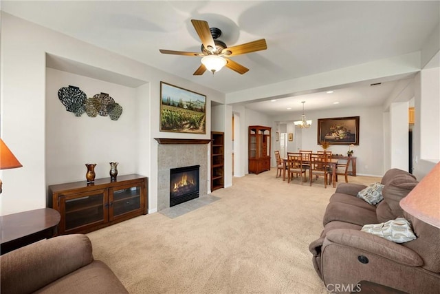 carpeted living area with a tile fireplace, ceiling fan with notable chandelier, built in features, baseboards, and recessed lighting