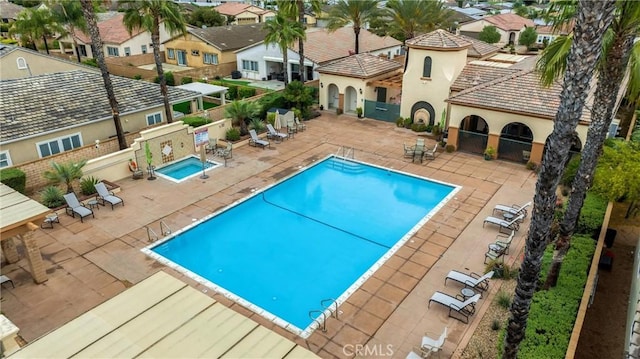 community pool featuring a patio area, fence, and a residential view