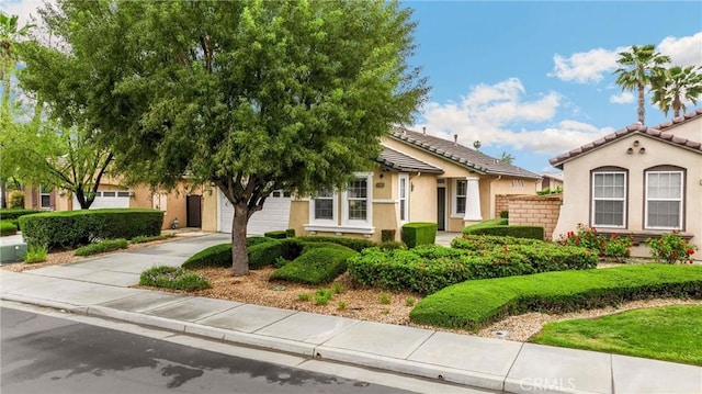 view of front of property featuring driveway, stucco siding, and a tiled roof
