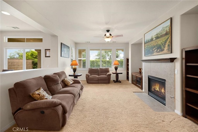 carpeted living area with ceiling fan, visible vents, and a tile fireplace