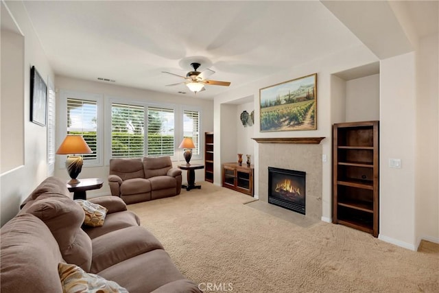 living area featuring visible vents, carpet flooring, a ceiling fan, baseboards, and a tiled fireplace
