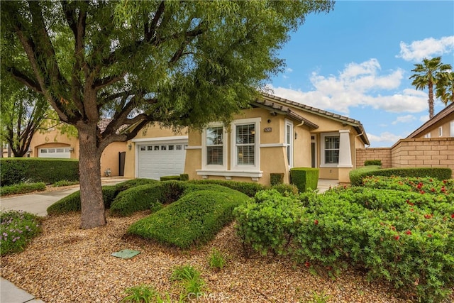 ranch-style home with fence, a garage, stucco siding, and driveway