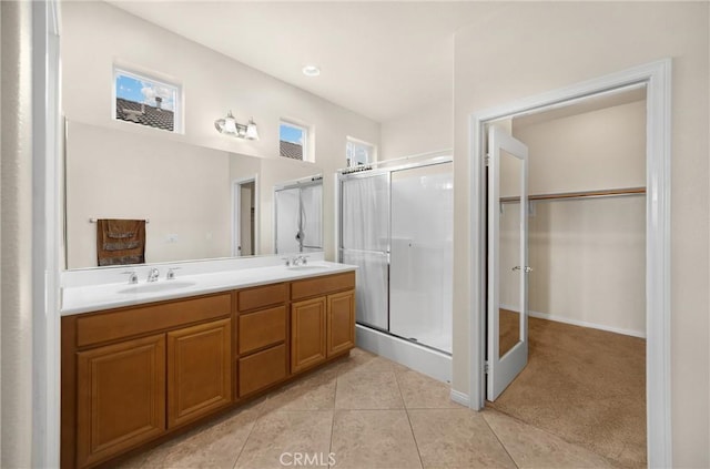 full bath with tile patterned floors, double vanity, a stall shower, and a sink