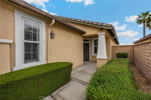 entrance to property with stucco siding and fence