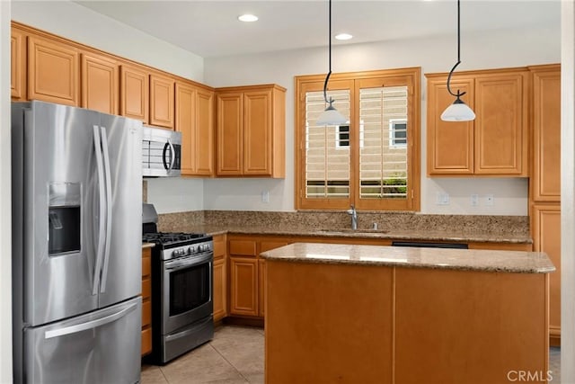 kitchen with stone countertops, pendant lighting, a sink, a kitchen island, and stainless steel appliances