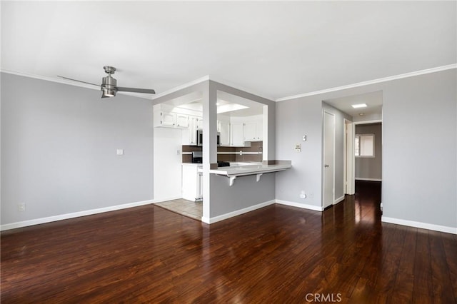 unfurnished living room with ornamental molding, dark wood-type flooring, baseboards, and ceiling fan