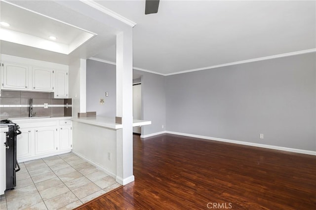 kitchen featuring ornamental molding, white cabinets, a sink, and tasteful backsplash