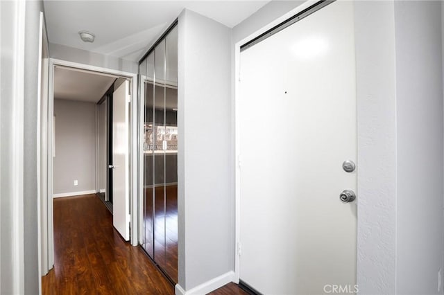 corridor featuring baseboards and dark wood-style floors