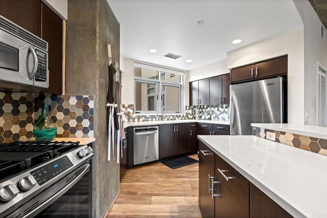 kitchen with dark brown cabinetry, backsplash, and appliances with stainless steel finishes