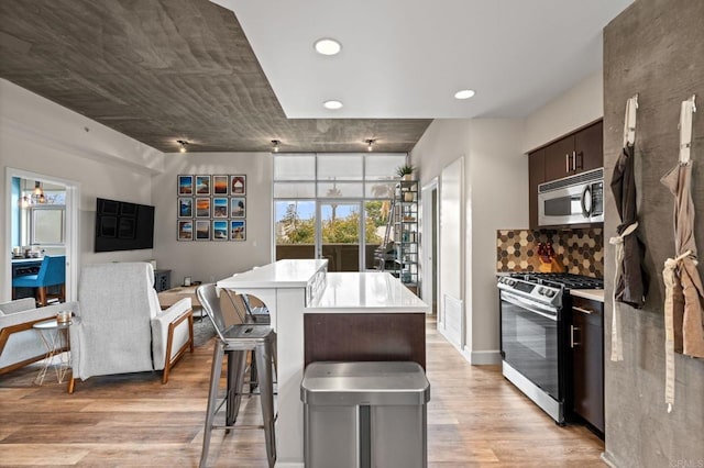 kitchen with light wood finished floors, a breakfast bar area, stainless steel appliances, light countertops, and recessed lighting