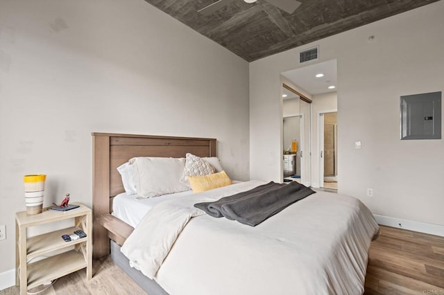 bedroom featuring electric panel, visible vents, wood finished floors, and baseboards