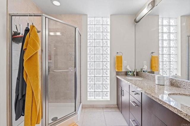 bathroom with double vanity, tile patterned flooring, a stall shower, and a sink