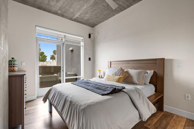 bedroom featuring baseboards, wood finished floors, and access to exterior