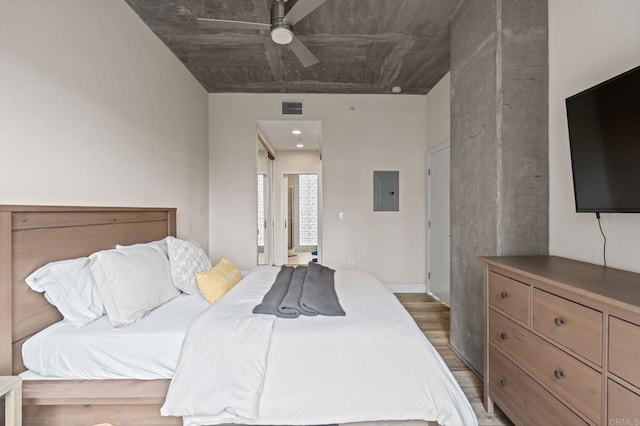 bedroom with ceiling fan, visible vents, electric panel, and wood finished floors
